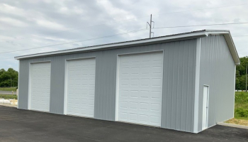 A JD Metals FastFrame Premium Steel Frame 3-car garage with tall doors, in Light Gray with Brite White trim.