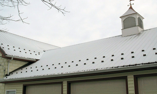 A snowy metal roof with Snow Defender Snow Guards.