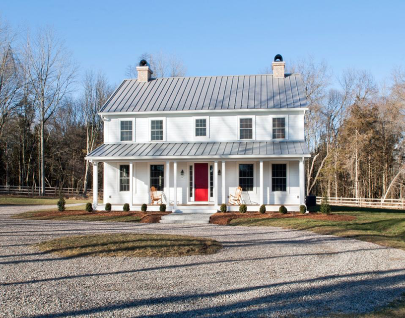 White colonial house with light gray standing seam metal roofing and red door