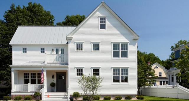 White colonial house with light gray standing seam metal roofing